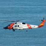 white and orange helicopter flying over the sea during daytime