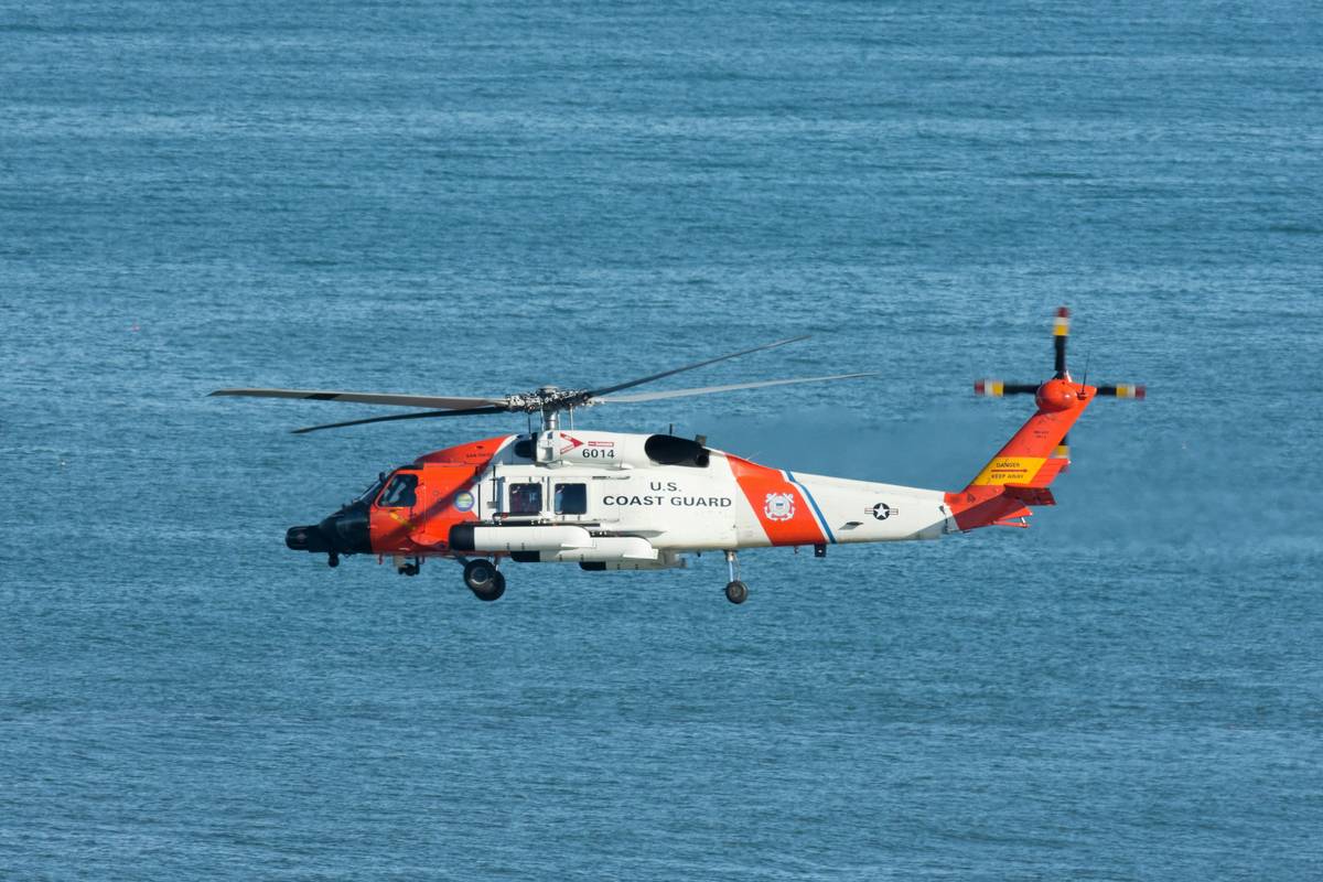 white and orange helicopter flying over the sea during daytime