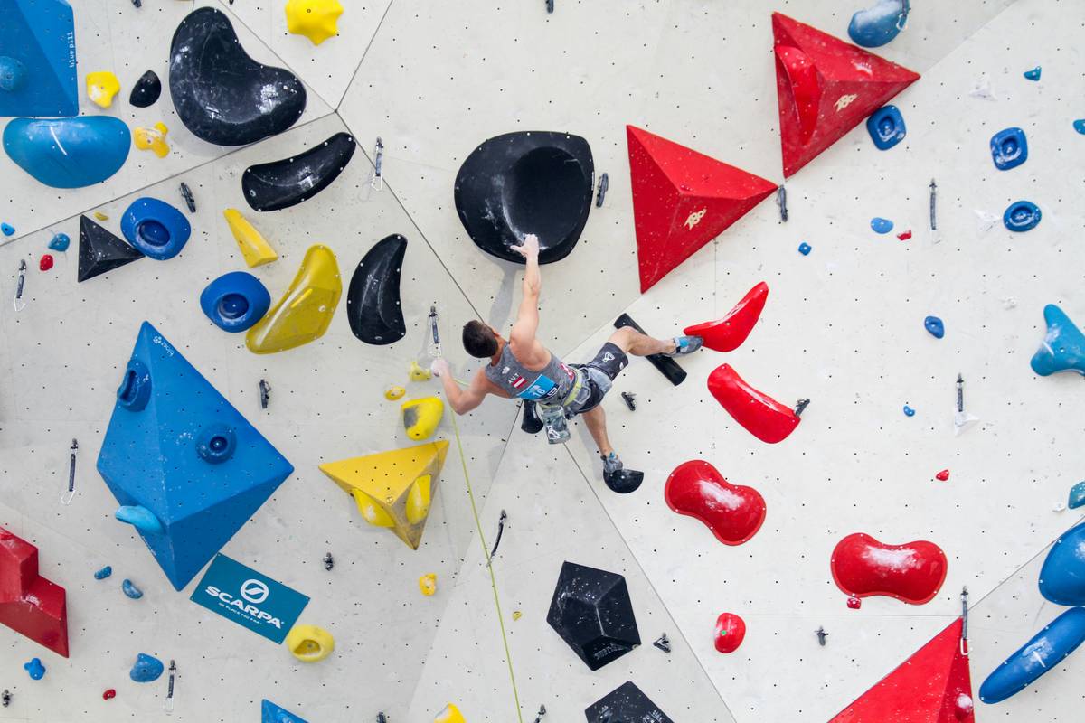 Climber inspecting gear against climbing safety standards checklist on granite wall