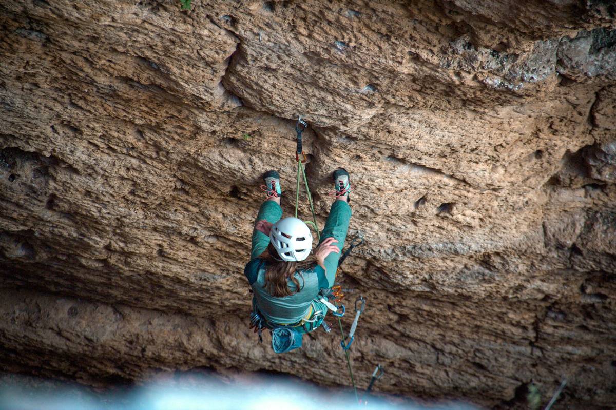 A person rock climbing up a textured cliff face
