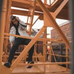 woman in blue denim jacket and black pants sitting on brown wooden ladder